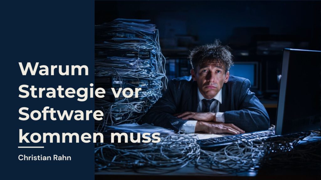 Erschöpfter Geschäftsmann im Anzug sitzt an einem chaotischen Schreibtisch voller Kabel und Papierstapel – Symbolbild für gescheiterte Digitalisierung ohne Strategie.